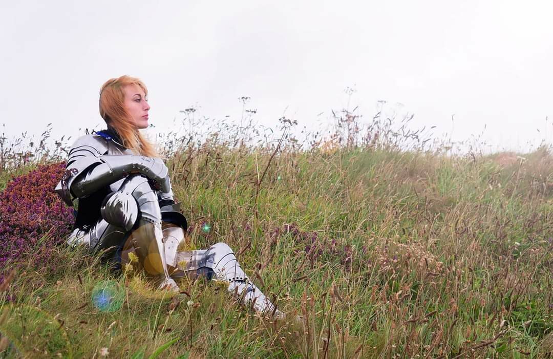 woman sat in field wearing suit of armour - Leeds castle