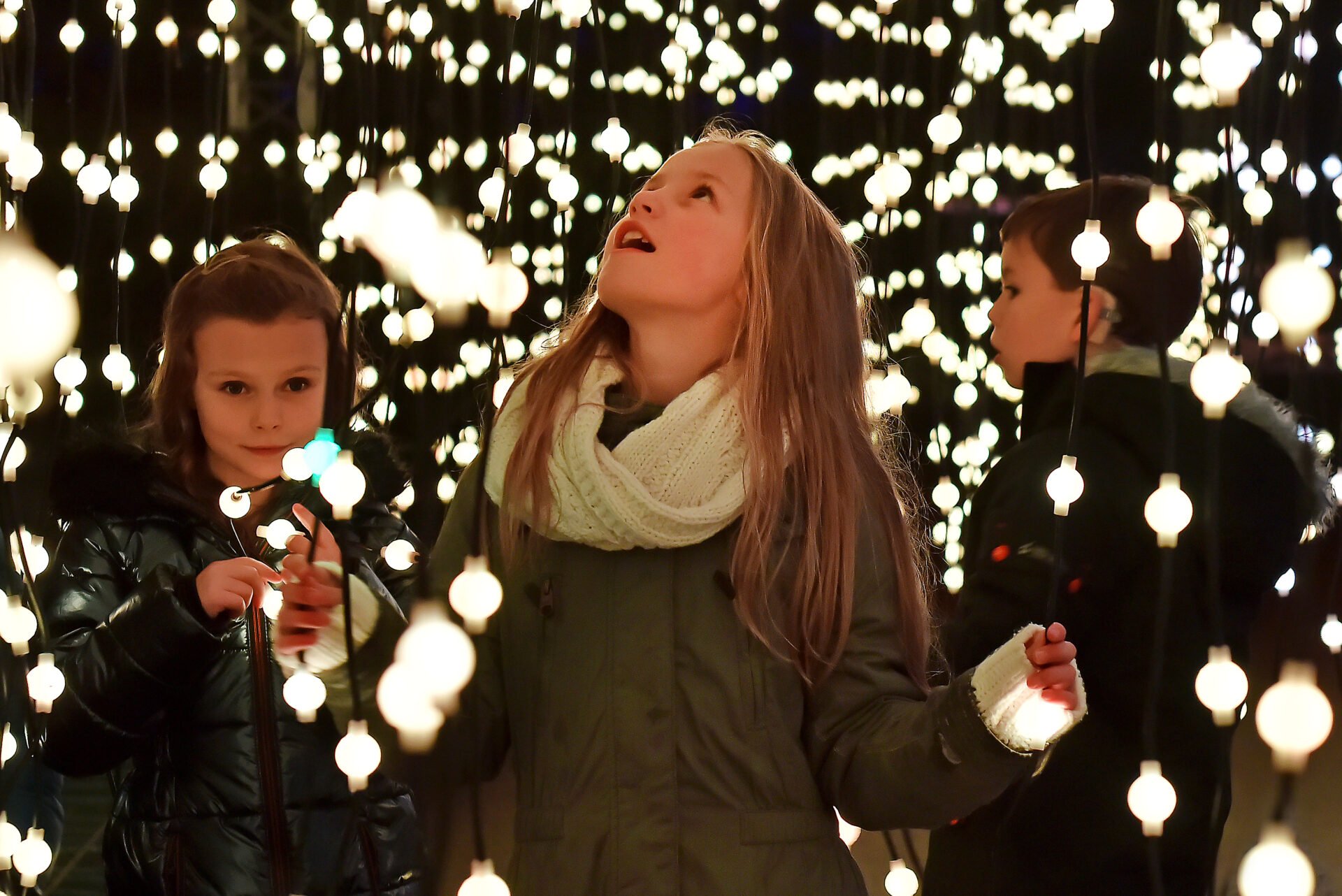 Children surrounded by string Christmas lights